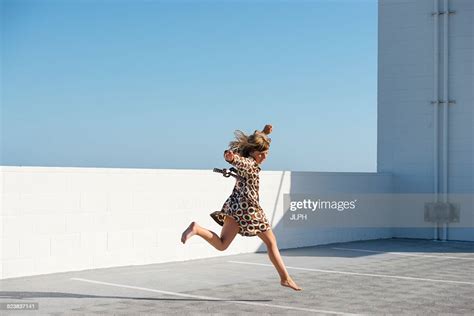 Girl Jumping Barefoot On Building Rooftop Photo Getty Images