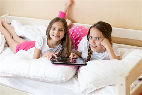 Duas Meninas Que Encontram Se Na Cama E No Vídeo De Observação No Tablet Pc Imagem De Stock