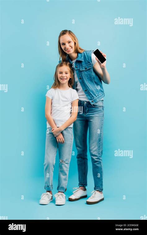 Full Length View Of Mother In Denim Clothes Showing Smartphone With