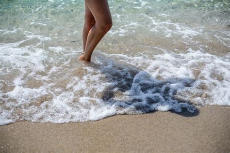 premium photo vacation concept close up of female legs standing in the surf of the sea