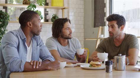 Three Male Friends Meeting In Coffee Shop Shot In Slow Motion Stock