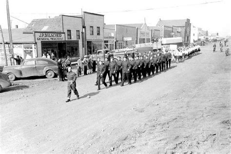 An Old Black And White Photo Of Men In Uniform Walking Down The Street