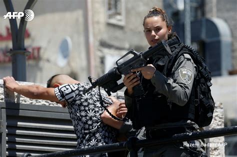 An Israeli Border Policewoman Holds Her Weapon While Checking The Id Of Palestinians At The Al