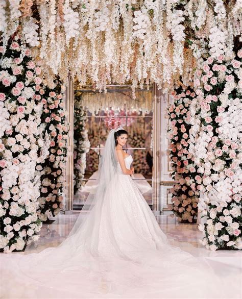 A Woman In A Wedding Dress Standing Under An Archway With White And