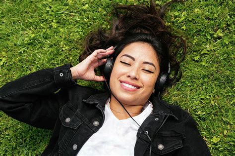 Overhead Shot Of A Cheerful Woman Lying On The Grass And Listening To Music Photograph By Cavan