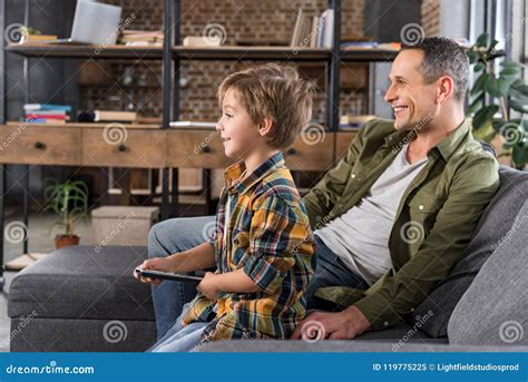 father and son watching tv at home while sitting stock image image of indoor fatherhood