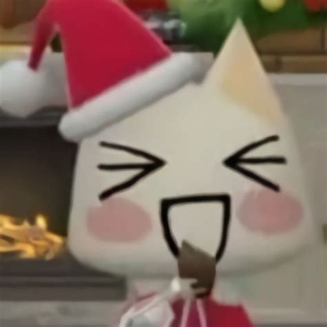 A White Cat Wearing A Santa Hat Next To A Fireplace