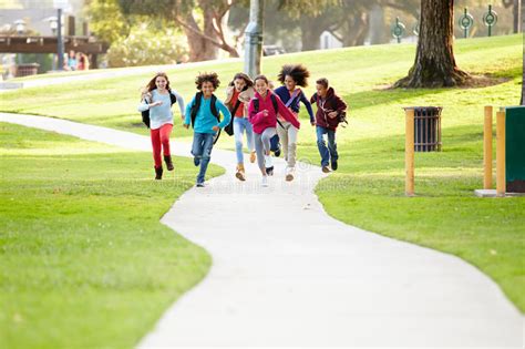 Group Of Children Running Along Path Towards Camera In Park Stock Image