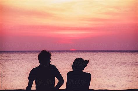 Silhouette Of A Couple Sitting On The Beach And Talking During The