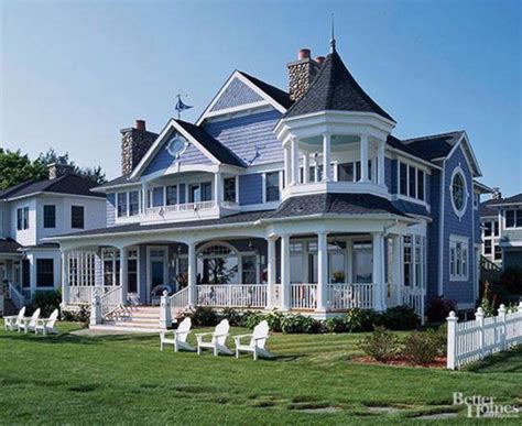 A Large Blue House With Two White Chairs In The Front Yard And An