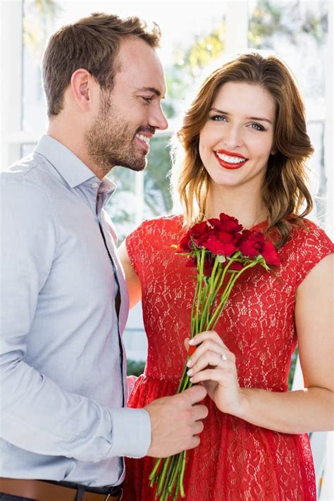 Man Offering Flower Box Of Red Roses To Beautiful Young Woman Stock