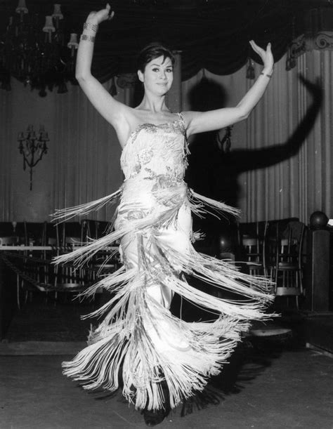 A Woman In A Dress Is Dancing With Her Hands Up And Legs Spread Wide Out