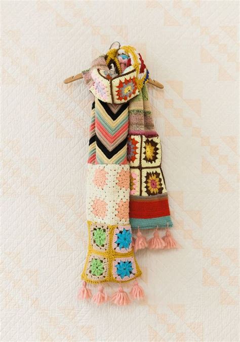 Multicolored Crocheted Scarfs Hanging From Clothes Pins On White Wallpaper