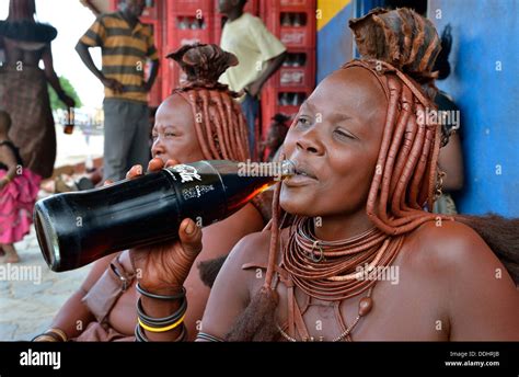 Traditionally Dressed Himba Woman Drinking A Coke In Front Of A Bar