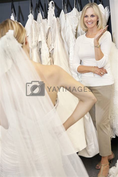 Happy Senior Mother Admiring Her Daughter Dressed Up In Wedding Gown By Moodboard Vectors