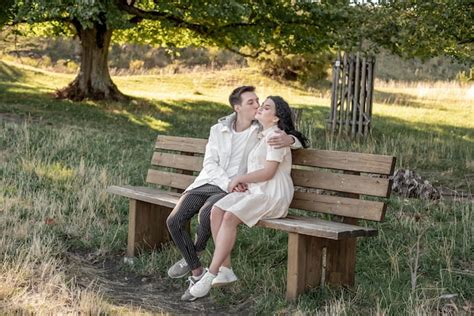premium photo a couple in love a guy and a girl sit on a bench and caress each other kiss