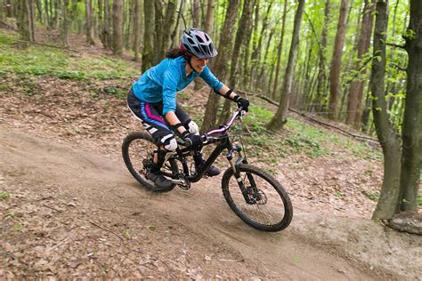 Young Woman Smiling While Riding Mountain Bike Downhill Forest Trail