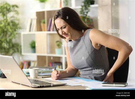Entrepreneur Woman In Pain Suffering Backache Sitting On A Desk At