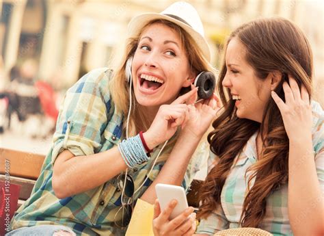 Foto De Listening To Music Two Girls Have Fun With Mobile Phone