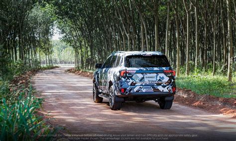 An Suv Driving Down A Dirt Road In Front Of A Row Of Bamboo Trees On