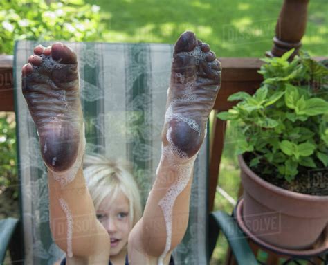 05:29 boy in dirty ankle socks the mud. Boy with dirty wet soapy bare feet raised - Stock Photo - Dissolve