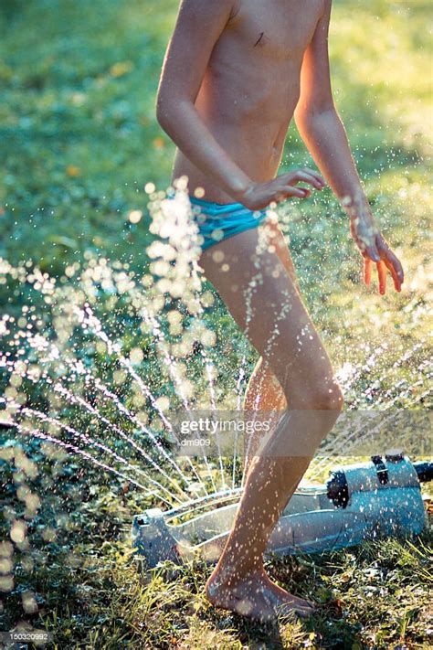 girl runs through sprinkler stock foto getty images