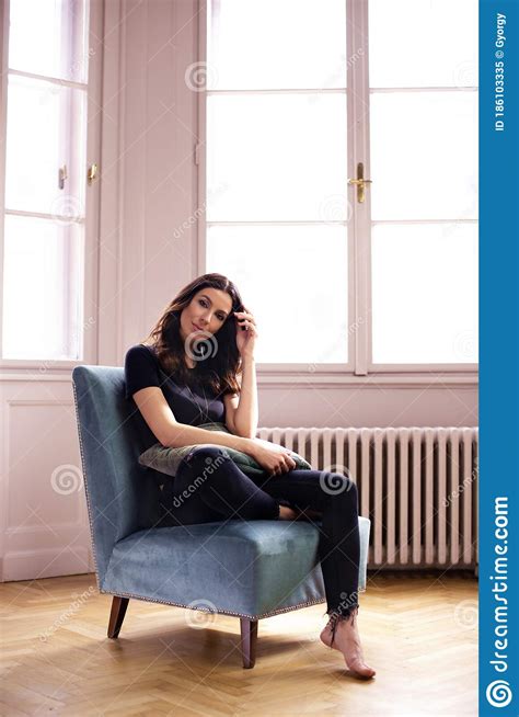 Attractive Woman Sitting In The Armchair While Relaxing At Home Stock