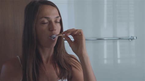 Young Woman Brushing Teeth With A Tooth Brush In Bathroom Stock Video