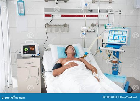 Patient Lying In Hospital Bed Surrounded By Medical Equipment Stock