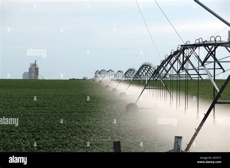 Commercial Farm Irrigation Sprayer Spraying Crop With Water Grain Elevator In Background Stock