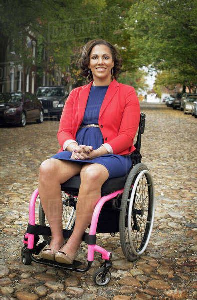 Disabled Woman Smiling In Wheelchair On Cobblestone Street Stock