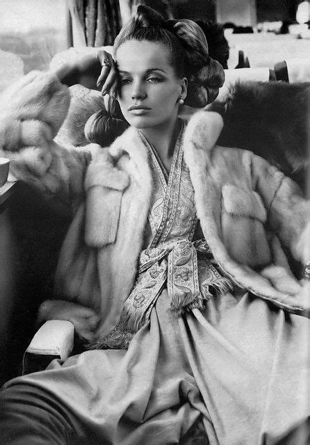 A Black And White Photo Of A Woman Sitting In A Chair Wearing A Fur Coat