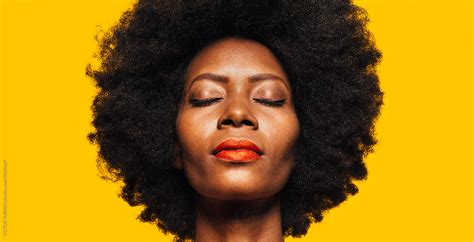 Beautiful Afro Woman Posing Over Yellow Background With Eyes Closed By Stocksy Contributor