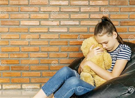 Upset Caucasian Teen Girl Sitting In Black Bean Bag Chair Hug Big Brown