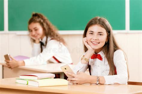 Schoolgirls In School Uniforms Sit For Couples In The Classroom Girls