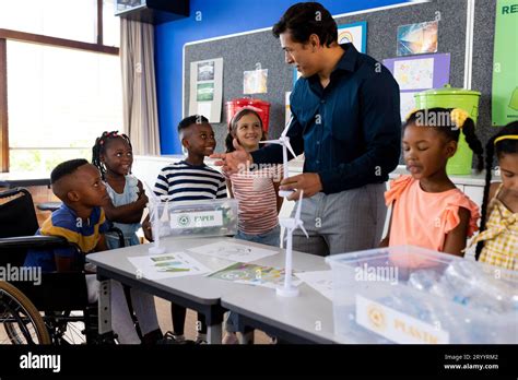 Happy Diverse Male Teacher And Children With Ecology Items In Class At