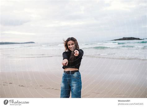 Porträt einer glücklichen jungen Frau am Strand auf den Betrachter zeigt ein lizenzfreies
