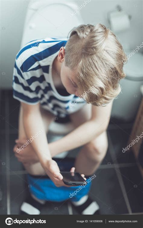 Teenage Boy Sitting On A Toilet With His Mobile Stock Photo By Jhandersen
