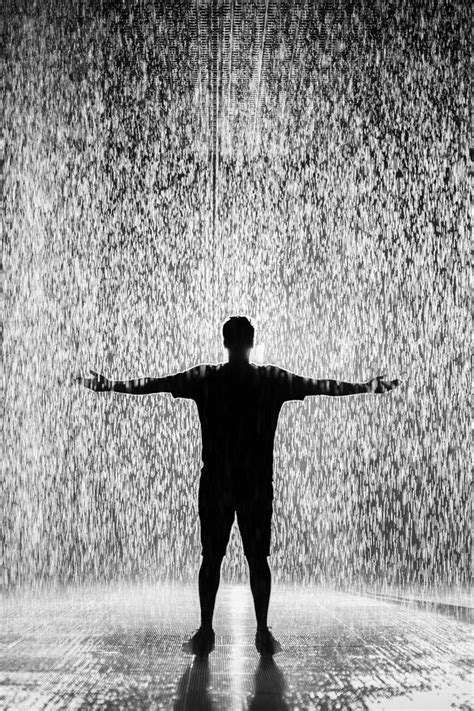 A Man Standing In Front Of A Rain Shower With His Arms Spread Out And Hands Outstretched