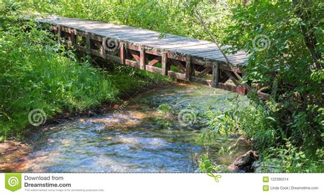 Rustic Wooden Bridge Crossing A Small Stream In The Woods Stock Photo