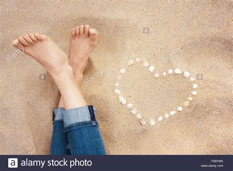 Female Feet Closeup Of Woman Standing At The Sandy Beach Next To The Shell Heart Stock Photo Alamy