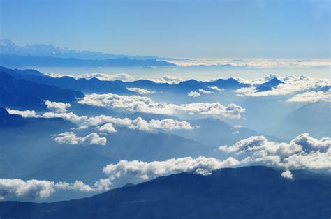 Scenic View Of Clouds Over Mountains Against Blue Sky · Free Stock Photo