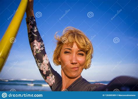 Young Attractive And Happy Blonde Surfer Woman In Swimsuit Holding Surf