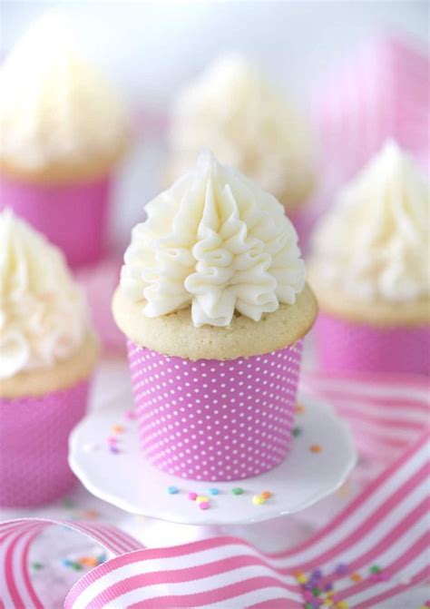 Cupcakes With White Frosting And Pink Polka Dot Paper Wrappers On A Plate