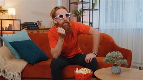 Premium Photo Man Sitting On Couch Eating Popcorn And Watching