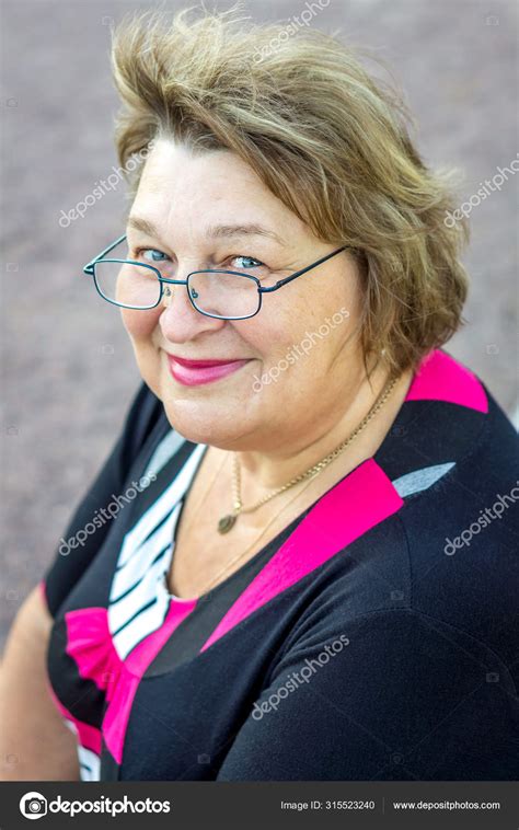 A Mature Woman In Glasses And Black Clothes Walks Around The Old Stock Photo Ramvseb