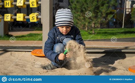 Little Boy Digging Sand In Sandpit With Shovel On Playground Concept