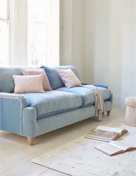 A Blue Couch Sitting In Front Of A Window Next To A Book On The Floor