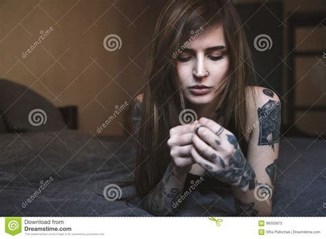 Young Tattooed Woman With Long Hair Lying On The Bed Stock Image