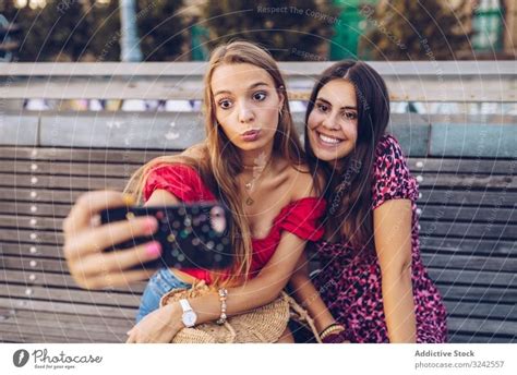 Laughing Women Taking Selfie On Wooden Bench At Street A Royalty Free